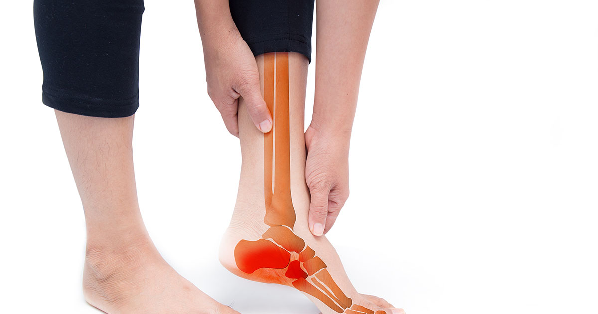 Person seated on a mat massaging their ankle and foot, with an anatomical x-ray overlay showing the bones and a highlighted inflammation site at the heel and ankle joint