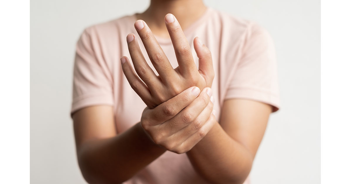 Woman holding her wrist and examining tingling fingers, illustrating nighttime hand numbness and nerve pain