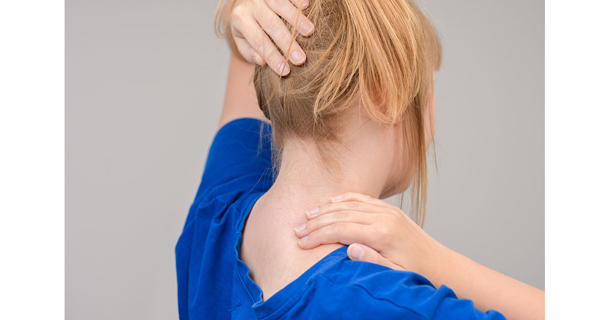Woman holding the back of her neck with both hands, illustrating cervicogenic headache pain radiating from the upper cervical spine
