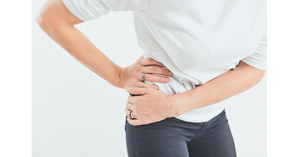 Person holding both hands over the hip and lower back area, illustrating the overlapping pain region between hip joint and lumbar spine