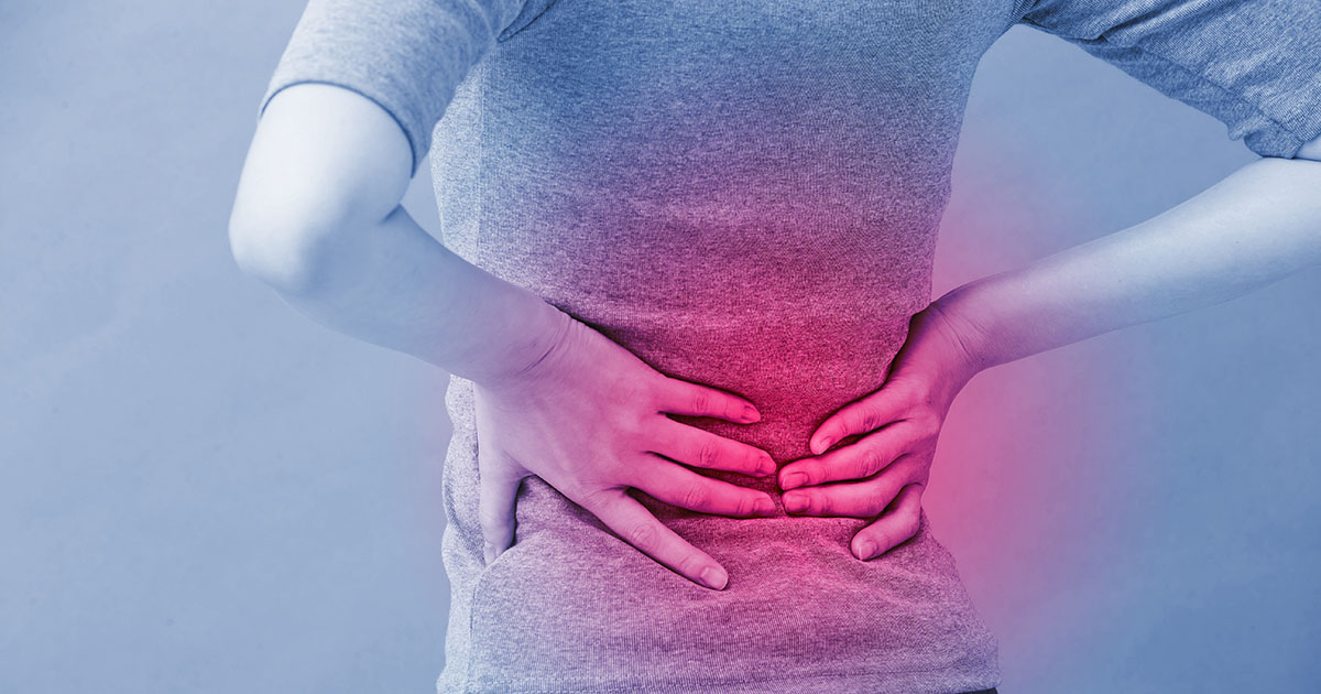 Person pressing both hands against their lower back and kidney area, with reddish pain overlay highlighting the affected region