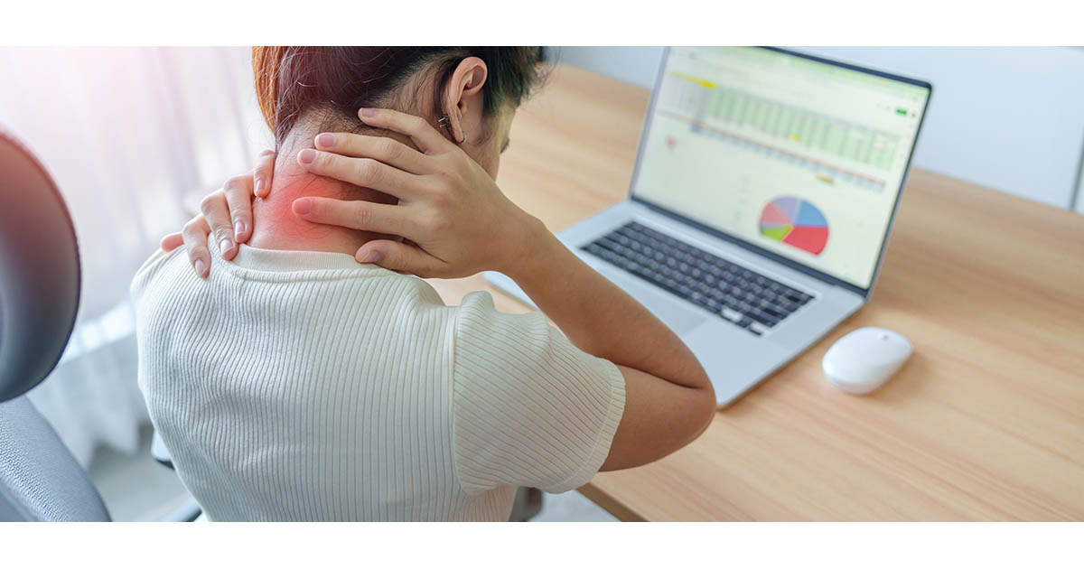 Woman sitting at a desk with her hand pressing on her neck and shoulder, with a red highlighted pain zone at the base of her neck