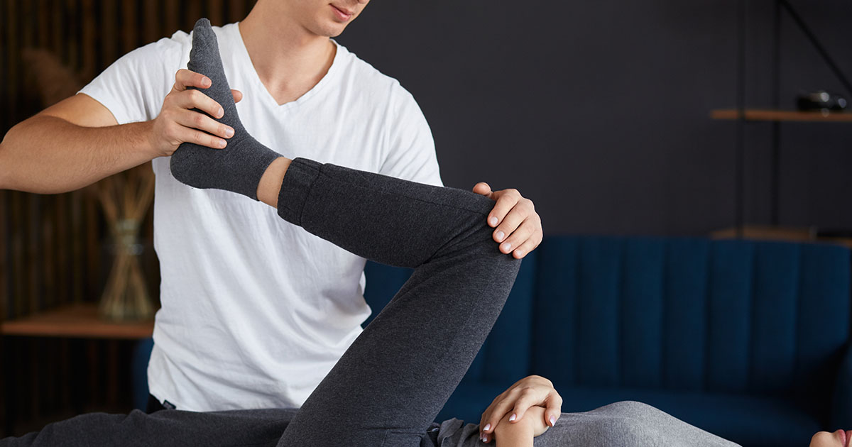 Physiotherapist working with a patient on hip and lower back mobility exercises in a rehabilitation clinic