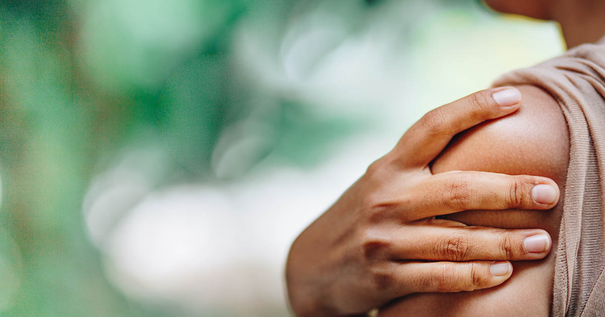 Woman in a pink shirt holding her hand with a red pain-highlight overlay on the palm, illustrating the tingling and numbness pattern of thoracic outlet syndrome