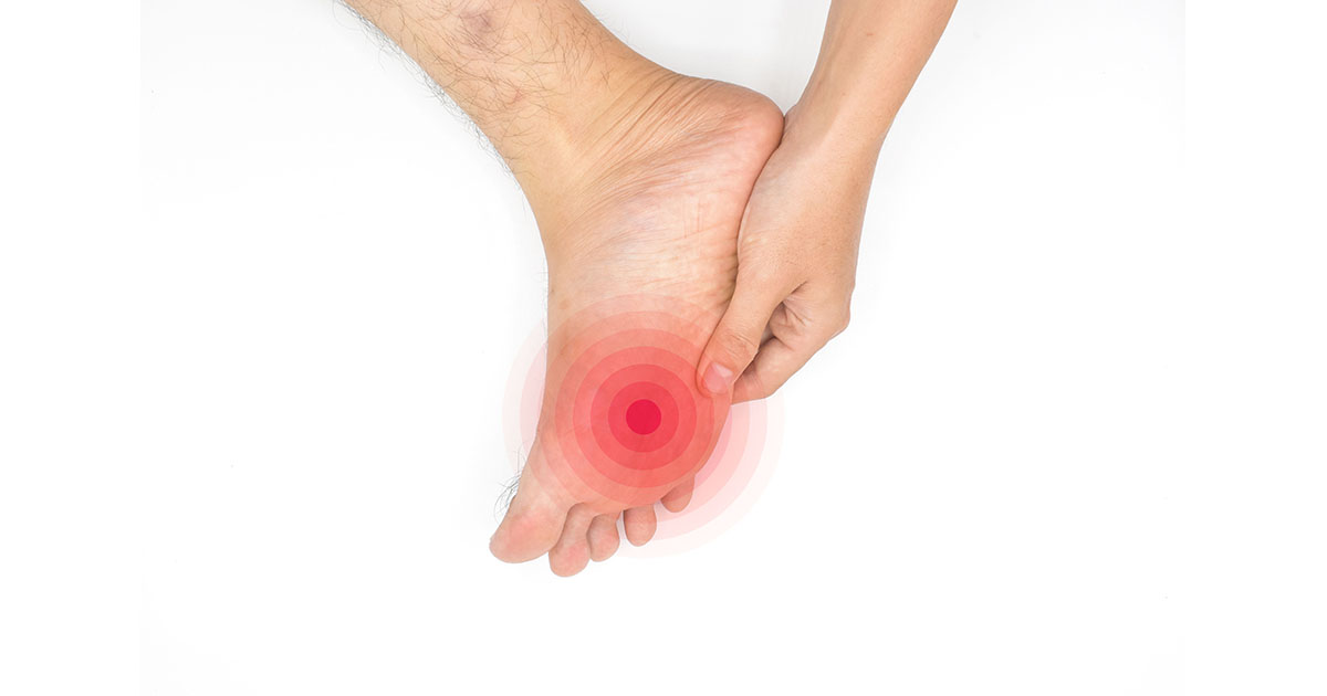 Man pressing his hand against the bottom of his foot with a red circle highlighting tingling and numbness sensation, illustrating toe numbness caused by lumbar nerve root compression