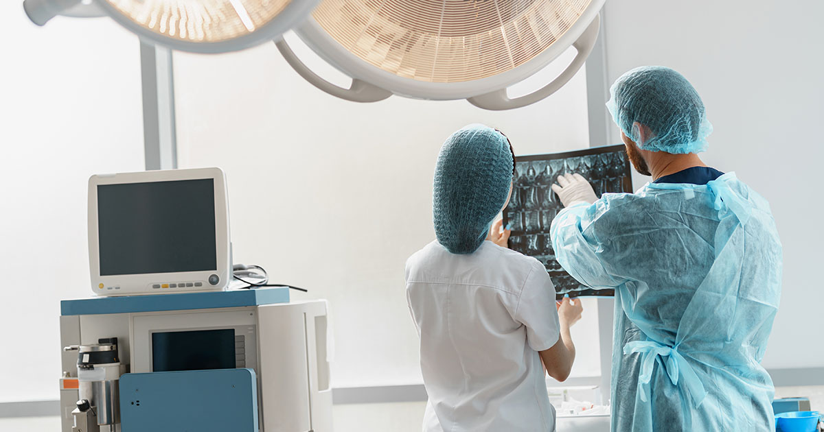 Physician and colleague in medical attire reviewing spine imaging scans together in a clinical setting