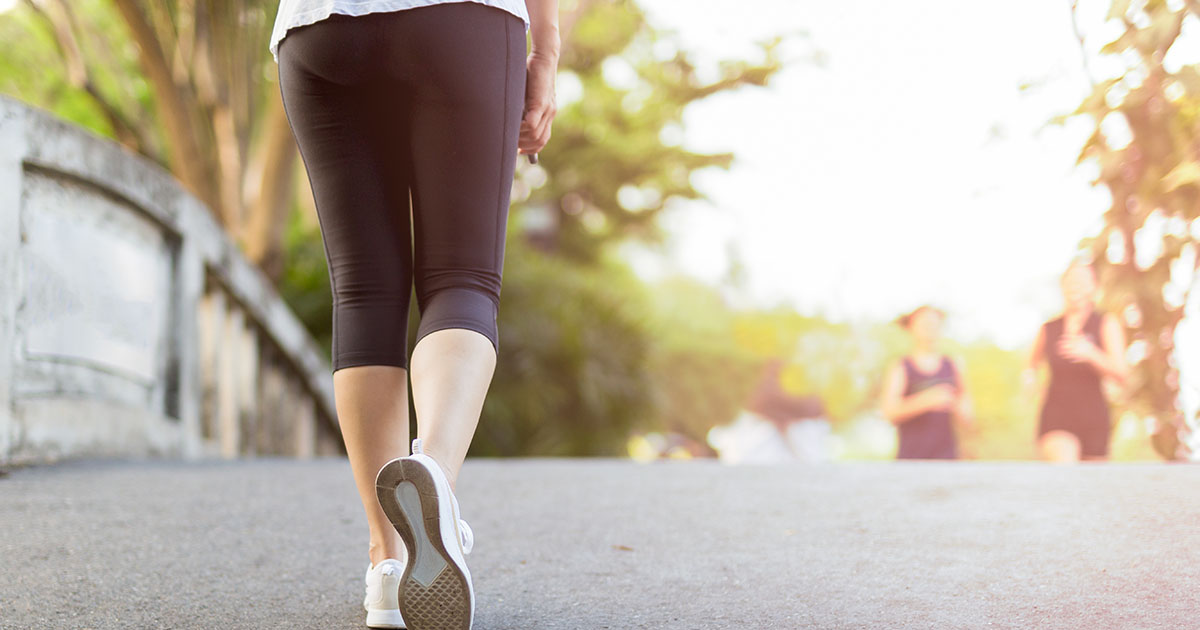 Woman walking briskly on a park path in early morning light, a common and evidence-backed approach to managing chronic low back pain