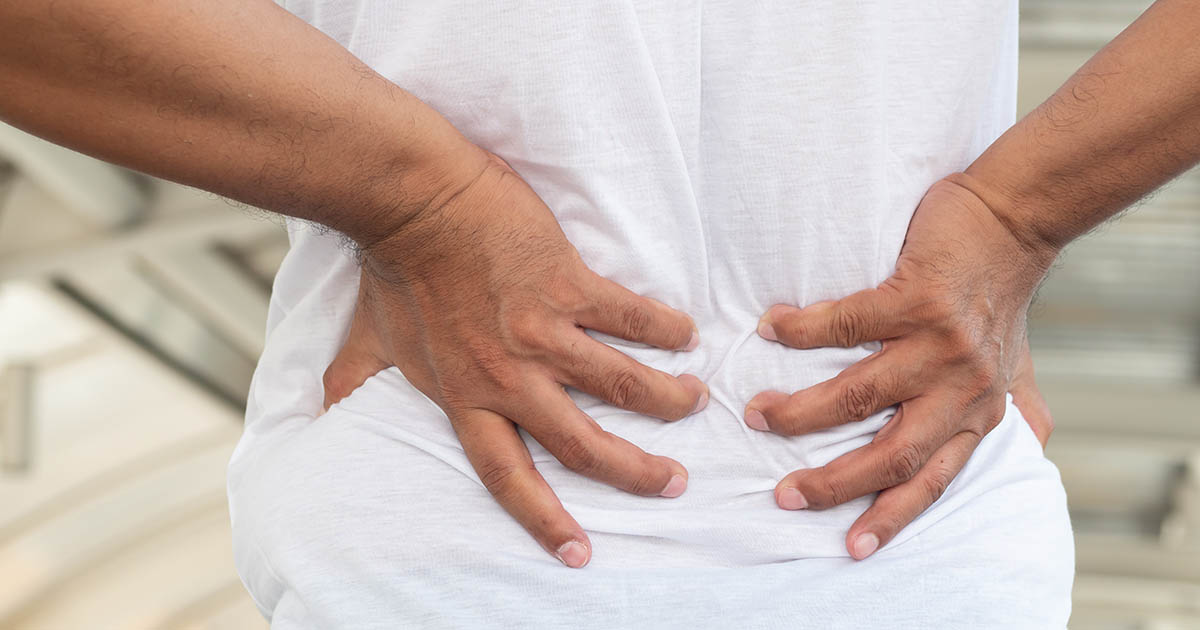 Man pressing both hands against his lower back in pain, illustrating the consequences of ignoring a herniated disc
