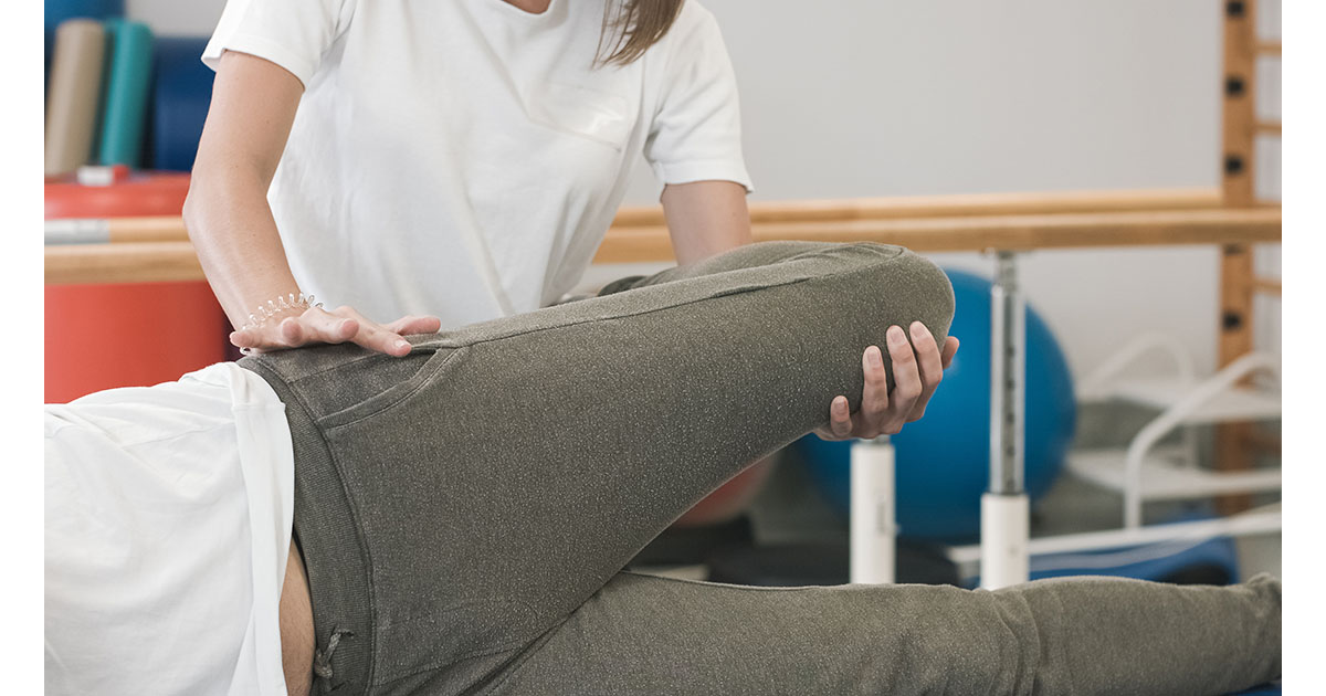 Senior man gripping his lower back in sharp pain while trying to stand up at home, illustrating recurring sciatica