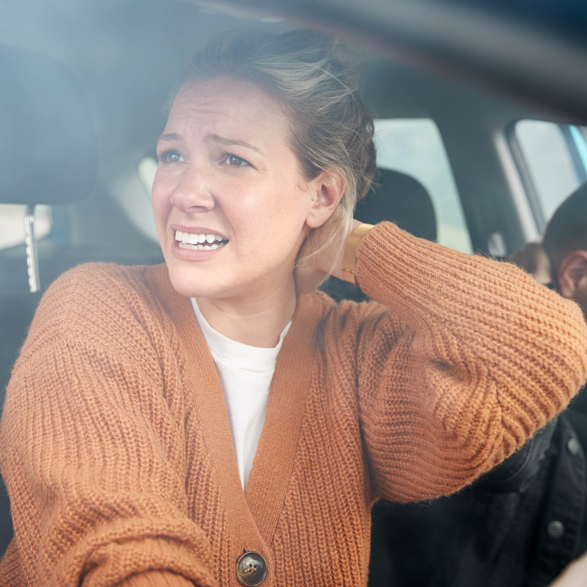 Driver holding her neck after a rear-end collision, the cervical flexion-extension pattern that produces whiplash and which Dr. Banman evaluates within the Florida 14-day PIP window