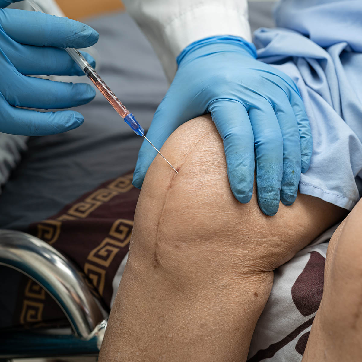 Doctor injects platelet-rich plasma into a senior patient's knee, a regenerative-medicine technique Dr. Banman uses to restart joint repair without surgery